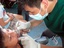 A boys gets tooth extraction as a dentist attends to him.