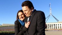 Jackie Lambie hugs Nick Xenophon outside Parliament House in Canberra, the flagpole visible behind them.