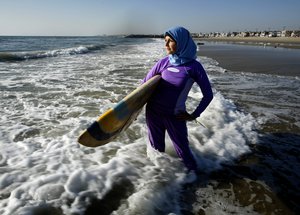 File - Sama Wareh walks along the sand dressed in swimwear designed for Muslim women in Newport Beach, Calif., Thursday, Feb. 15, 2007. Several French towns have banned the full-body swimsuit - named the burkini - due to public order and security concerns.