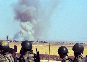 Turkish soldiers stand as smoke billows from the Syrian town of Ayn al-Arab or Kobani following the attacks by IS militants as seen from the Turkish side of the border in Suruc, Turkey, Thursday, June 25, 2015.