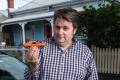 Comedian Dave O'Neil poses for a photo with his VW Golf TSI while holding a model of his first car (Holden Torana).