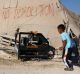 In this Tuesday, July 21, 2015, photo, a Palestinian boy runs outside his family tent in the village of Susiya, south of ...