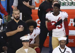 San Francisco 49ers quarterback Colin Kaepernick, middle, sits during the national anthem before an NFL preseason football game against the San Diego Chargers