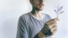 A man in a striped t-shirt holds a leaf.