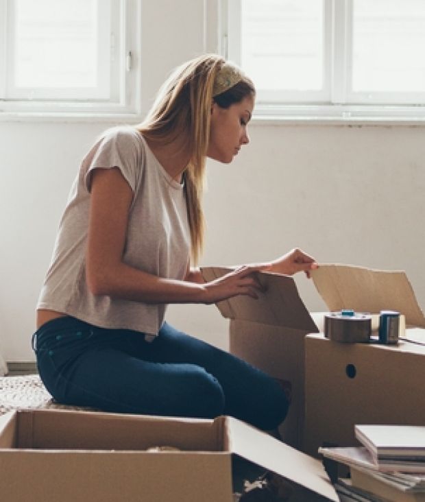 Young woman unpacking her things after moving into a new flat.