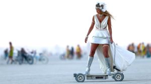 In this Wednesday, Aug. 31, 2016 photo, a woman rides an electric scooter during Burning Man at the Black Rock Desert ...