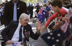 A war veteran gives a high five to a boy as he participates in the annual Australia and New Zealand Army Corps (ANZAC) parade in Sydney, Australia