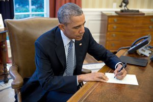 President Barack Obama signs a letter to Ileana Yarza, a 76-year-old letter writer in Cuba, in the Oval Office, March 14, 2016