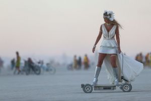 In this Wednesday, Aug. 31, 2016 photo, a woman rides an electric scooter during Burning Man at the Black Rock Desert ...