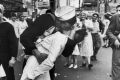 A jubilant American sailor clutching a white-uniformed nurse in a back-bending, passionate kiss as he vents his joy ...