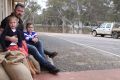 Glenelg Inn publican Troy Robbins and his children Marlee and Nate sit on sandbags outside the hotel at Casterton. 