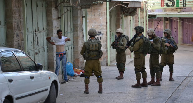 Israeli forces force Palestinian to lift up his shirt during a 'control'