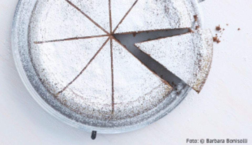 Ein Kuchen mit Puderzucker darauf. Ein Stück wurde schon abgeschnitten.