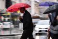 The rain falls on pedestrians crossing Flinders Street on Tuesday.