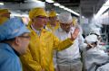 Apple Chief Executive Officer Tim Cook (2nd L) talks to employees as he visits the iPhone production line at the newly ...