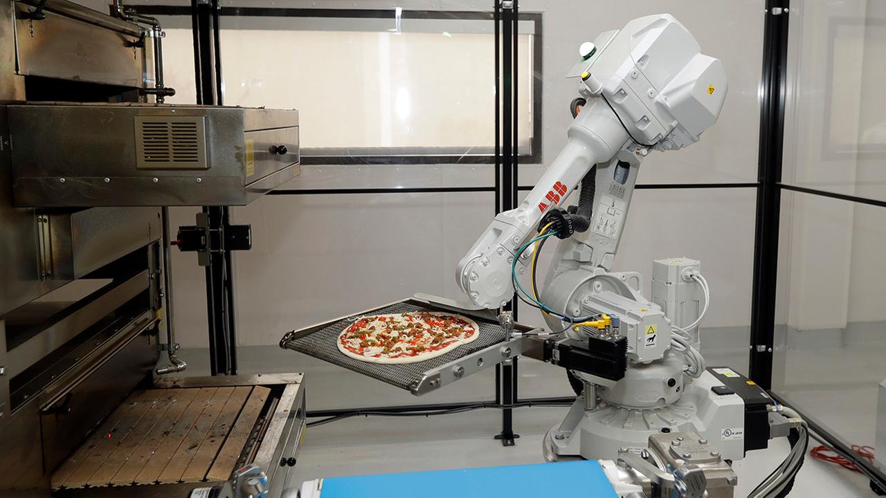 A robot places a pizza into an oven at Zume Pizza in Mountain View, California