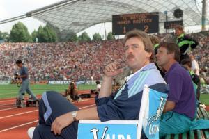 Rostocks Trainer Uwe Reinders (vorn) schaut bei einer 2:1-Führung zufrieden in die Runde am 10.08.1991 im Münchner Olympiastadion. Fußball-Bundesliga-Neuling FC Hansa Rostock schlägt als Ost-Meister den Bundesliga-Rekordmeister FC Bayern München mit 2:1. Die Rostocker steigen am Saisonende aus der 20er Liga als Drittletzter gleich wieder ab, und Reinders muss schon zuvor, am 6. März 1992, seinen Platz räumen. Der FC Bayern rangiert bei Meisterschaftsende nur auf Platz zehn. +++(c) dpa - Report+++ | Verwendung weltweit