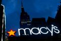 The Empire State building in the background, the Macy's logo is illuminated on the front of the department store in New ...