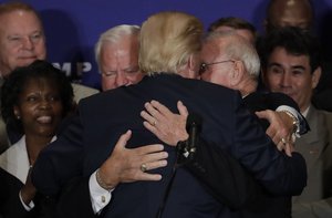 Republican presidential candidate Donald Trump hugs two Medal of Honor recipients during a gathering with military leaders and veterans at the new Trump International Hotel in Washington, Friday, Sept. 16, 2016.