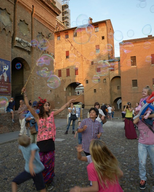 Children play in front of the 'Castello Estense', Ferrara.