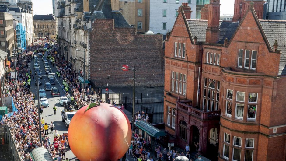 Members of the public gather to watch a giant peach as it is moved through the centre of Cardiff as part of a street ...