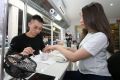 Nail artist Jonny Diep Pham working on Tara Micallef's nails in his Penrith salon Nailicious. 