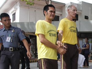 File - Peter Gerald Scully of Australia, right, walks in handcuffs with an unidentified detainee as they arrive at Cagayan de Oro city hall in southern Philippines on Tuesday, June 16, 2015.