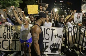 Protesters raises their fists as they observer a moment of silence as they march in the streets of Charlotte, N.C. Friday, Sept. 23, 2016.