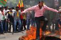 An activist jumps over a burning effigy during protests in Bangalore this week that forced many large Indian and foreign ...