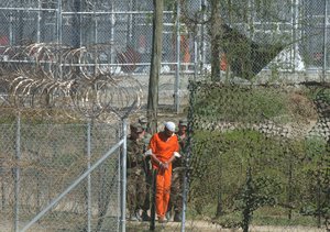 In this March 1, 2002 file photo, a detainee is escorted to interrogation by U.S. military guards at Camp X-Ray at Guantanamo Bay U.S. Naval Base, Cuba.