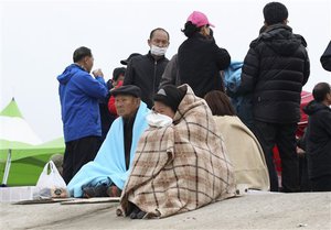 File - Relative of passengers aboard the sunken ferry Sewol in the water off the southern coast wait for their missing loved ones at a port in Jindo, South Korea, Saturday, April 19, 2014.