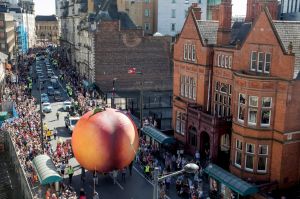 Members of the public gather to watch a giant peach as it is moved through the centre of Cardiff as part of a street ...