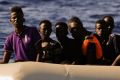 Migrants fleeing Libya on a dinghy wait to be rescued in the Mediterranean Sea.