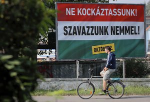 A man rides a bicycle by a poster that reads in Hungarian "Let’s not risk it! Let’s vote no! October 2", supporting Hungarian Premier Minister's Viktor Orban policies on migrants in Budapest, Hungary, Saturday, Oct. 1, 2016.