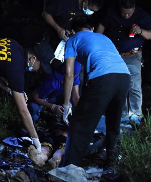 Police inspect the scene of one of the three men slain in a drug related killing in Caloocan, Manila, Philippines.