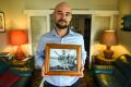 Duncan Williams holds a photo of his WWII RAAF pilot grandfather sitting on the wing of a Spitfire plane. 