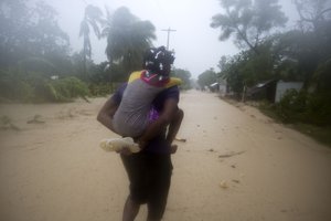 A woman and a child walk in a waterlogged street as they head to a shelter under the pouring rain caused by Hurricane Matthew, in Leogane, Haiti. Tuesday, Oct. 4, 2016.