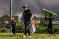 A bushfire rages behind holidaymakers at Currarong, looking south towards the fire.