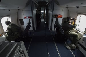 Chief Naval Aircrewman (Operator) Samuel Judd, left, and Naval Aircrewman (Operator) 2nd Class Carlos Ibarra, both assigned to Patrol Squadron (VP) 16, search out the windows of a P-8A Poseidon while flying over the Indian Ocean in support of the international effort to locate Malaysia Airlines flight MH370, 8 April, 2014.