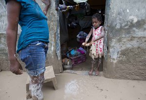 A girl helps her mother to remove mud from her house after Hurricane Matthew flooded their home in Les Cayes, Haiti, Thursday, Oct. 6, 2016.