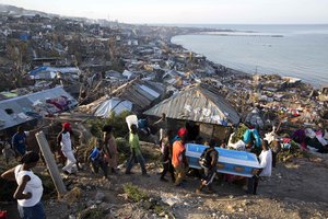 Residents carry a coffin containing the remains of a pregnant woman, a victim of Hurricane Matthew, in Jeremie, Haiti. Friday, Oct. 7, 2016.