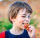 Kid or young boy making funny faces, winking and eating