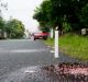 A candle marks the spot where three bodies were dumped by unknown men along a secluded street in suburban Quezon City ...