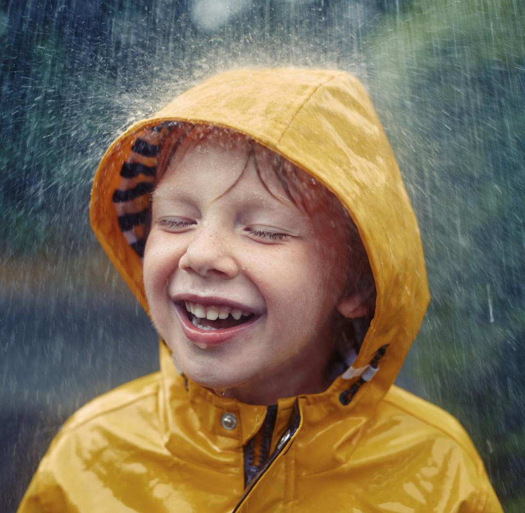 Happy smiling little boy in the rain