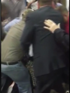 Supporters at a Donald Trump rally in Birmingham, AL, kick and punch a Black Lives Matter protester to the ground. Image via screenshot.