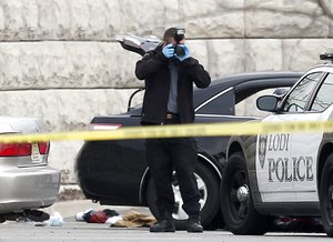 An official takes photographs at the scene where a police officer was involved in a shooting in a shopping center, Tuesday, April 22, 2014, in Garfield, New Jersey, USA.