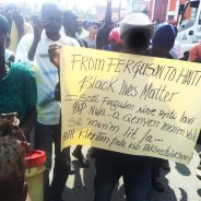 Haiti has been on the march for months. These politically astute protesters make their purpose clear. The face of the person holding the sign has been blurred to protect his identity.