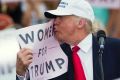 Republican presidential candidate Donald Trump kisses a 'Women for Trump' sign at a campaign rally in Florida. 