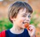 Kid or young boy making funny faces, winking and eating