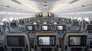 Entertainment monitors sit on the back of passenger seats in the economy class cabin of an Airbus SE A350 aircraft, ...